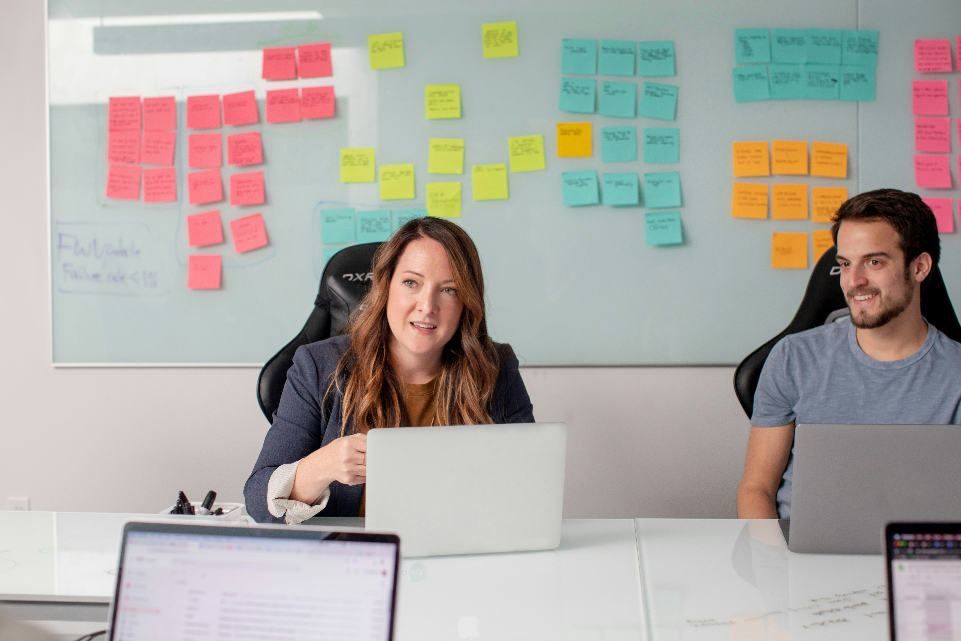 Colleagues working together in a bright office with a wall of collaborative sticky notes